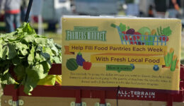 A wagon filled with fresh veggies with a Historic Lewes Farmers Market sign that says "Help Fill Food Pantries Each Week with Fresh Local Food"
